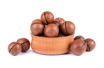Macadamia nuts in wooden plate, isolated on white background. Unshelled macadamia.