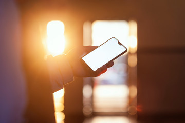 Mockup of the smartphone in the hand of the guy against the sunset.