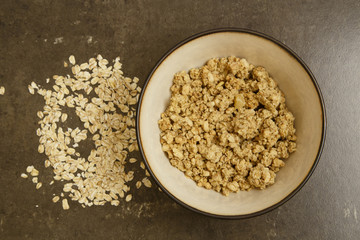 Flakes from different types of cereals in a gray deep plate on a gray tile