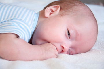 The baby cries and pulls the handle into his mouth because of the cutting teeth. Selective focus.