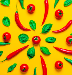 Above view at Chili pepper and tomatoes with basil on yellow background