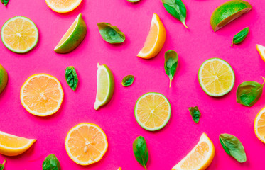 Above view at cutted lemons and limes on pink background