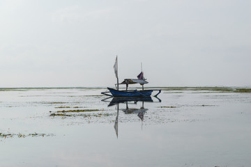 Obraz premium Lonely blue boat floating in the middle of the ocean during low tide