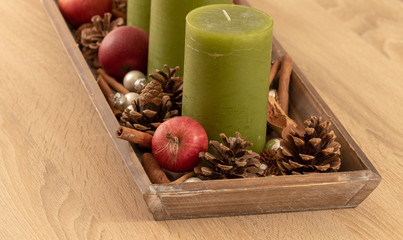 Close up of advent wreath with apples cones and green candles on wooden table