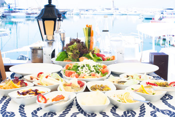 Seafoods, fish, salad and mezes on the table near the sea