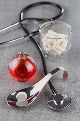 close-up of a large white tablet on a metal spoon on background a stethoscope and medication syrup
