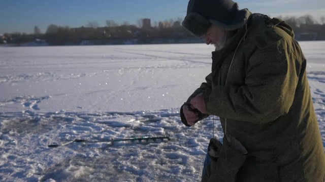 Old man caught the fish perch on winter fishing. 4К
