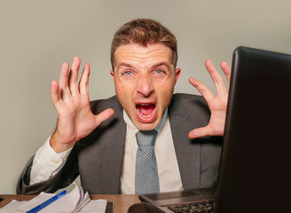 stressed and overwhelmed businessman in suit and tie working at office laptop computer desk...