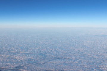 View of blue sky from horizon. View from the airplane porthole. Blue sky, white air clouds.