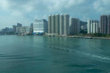 Waves on the water, traces of the boat. Tall city buildings, waterfront. City by the sea.