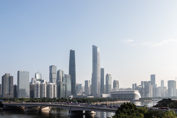Modern city with skyscrapers. City buildings, a bridge across the river, driving cars on the bridge. High towers of a business center. Modern architecture of buildings.