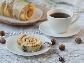 Christmas sponge lime roll cake with poppy and caramel on a wooden dish with cu of tea. Chocolate yule log cake. xmas or new year theme. Slice of cake. close up, seective focus