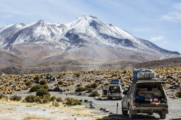 Desert landscape with jeeps and snowed peaks at the background © Thiago