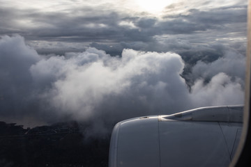 Flying through the clouds, below the earth, the sun shines through the clouds. Jet engine aircraft....