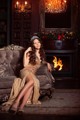 Fototapeta na wymiar Beautiful girl model celebrates Christmas or New Year in a classic interior, near a New Year tree, spruce. Holiday woman with gifts