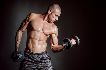 Fototapeta na wymiar A man shakes his arm muscles. Man with dumbbells. Strong man. Strength exercises. Muscle man. Pumped up muscles. Muscle mass. Dumbbell. Sport equipment.
