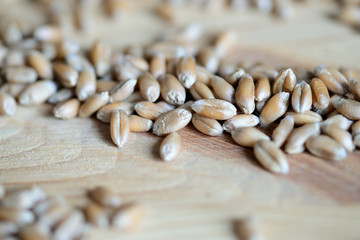 Fototapeta premium Scattered wheat grains on wooden background close up