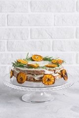 Cake on glass stand decorated with rosemary dried mandarin slices