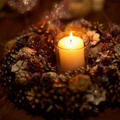 Advent decoration, wreath, candle. In the dark a candle in a beautiful decorative wreath is burning.