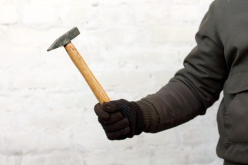 Hammer with wooden handle in man hand working in black gloves on white background close-up