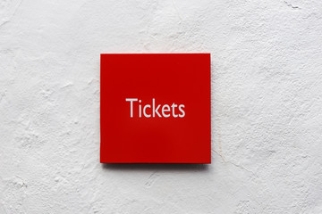 Red signboard with the word Tickets on white wall