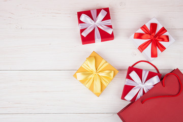 Red paper gift bag with presents boxes on white wooden background. Copy spase for your text