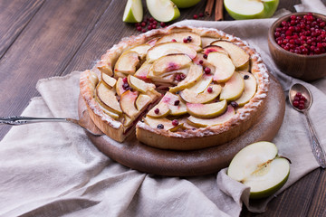 Homemade apple pie and ingredients on wooden background.