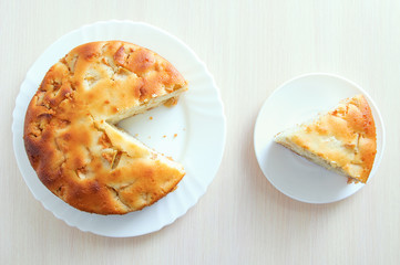 Sliced piece of cake on a white plate. Pie on the kitchen table. View from above.