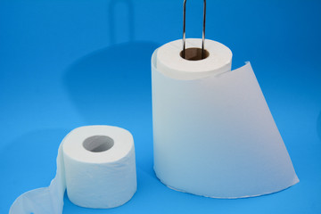 Paper towels and toilet paper on a blue pastel background with natural light. 