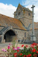 Fototapeta na wymiar Ville de Genêts, l'église Notre-Dame (XIIe-XIVe) et son cimetière, fleurs rouges en premier plan, département de la Manche, France 