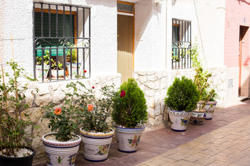 Fototapeta na wymiar Ceramic flower pots on a cozy Mediterranean street in the old town of Relleu, Spain.