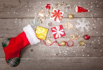 Christmas gifts flying out of Santa Claus stocking on wooden background