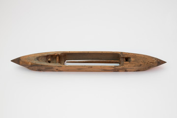 Very old wooden shuttle used in weaving, upper side, isolated on white background.
