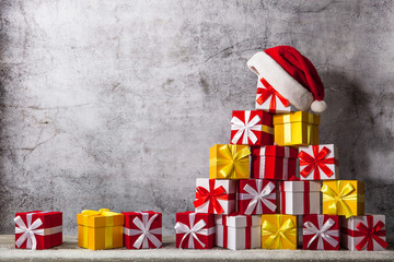 Christmas gift boxes in front of concrete wall shape of pyramid with Santa Claus hat on top. View with copy space for your text