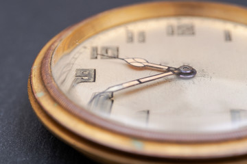 Old antique pocket watch on natural stone background.