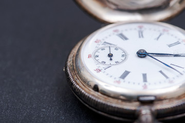 Old antique pocket watch on natural stone background.