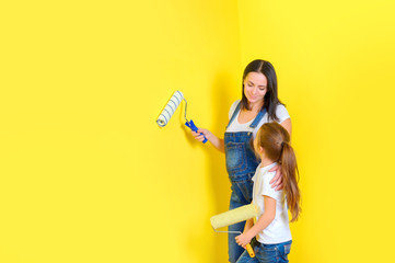 mother with her little daughter will brighten the walls with rollers in the room, repairs in the house