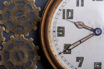 Antique pocket watch and old vintage hour metallic gears on natural stone background.