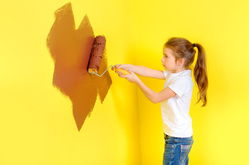 beautiful little girl is painting a wall, repair in the room