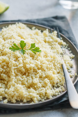 Couscous on a black ceramic plate on a table. The concept of vegetarian and healthy food.