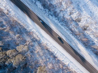 Cars on road in winter with snow covered trees. Aerial photo