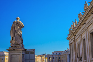 Statue of St. Peter in St. Peter's Square, Vatican City, with the front of the famous Basilica.