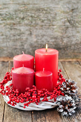 Four candles in a white wreath with red berries on a wooden rustic background. advent calendar for...