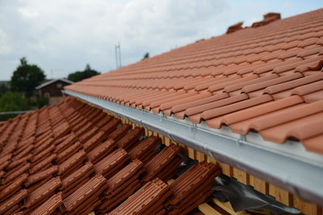 Fototapeta na wymiar Ziegeldach Bauarbeiten beim Hausbau: Dachdecker Dach mit Dachziegel Ziegelstein Tradition