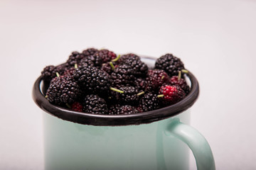 Top view of summer berries (blueberry and blackberry) iron mug isolated on white background.