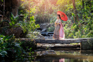 Beautyful Thai woman wearing thai traditional clothing with red umbrella.