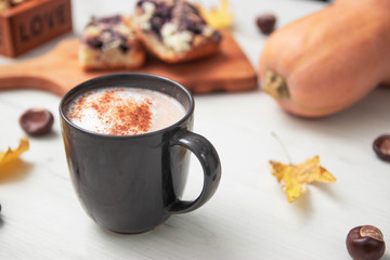 Piece of pumpkin pie with cinnamon and coffee with milk in brown dishes on  background with autumn yellow leaves - top view close up photography of seasonal american traditional sweet baked food.
