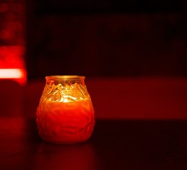 Red Wax Candle in Glass against red bokeh background. Concept of harmony, balance and meditation, spa, relax.  
