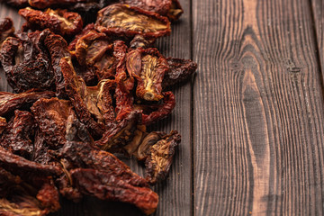 Dried vegetables chips from tomato on wooden background. Organic diet and vegan food