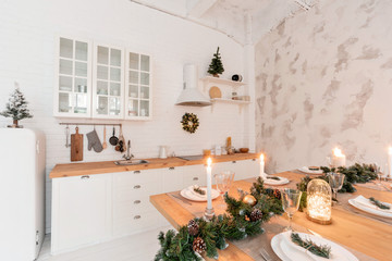 Loft style Apartment, large spacious living room with dining table and kitchen. Room with Christmas tree. Light white brick wall.
